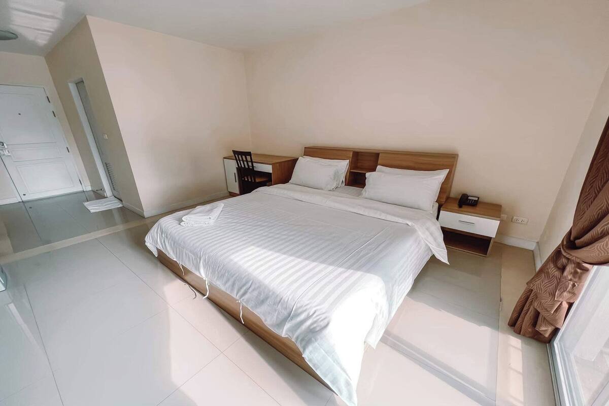 Una habitación de hotel con una cama grande, mesitas de noche, un escritorio y una silla.
