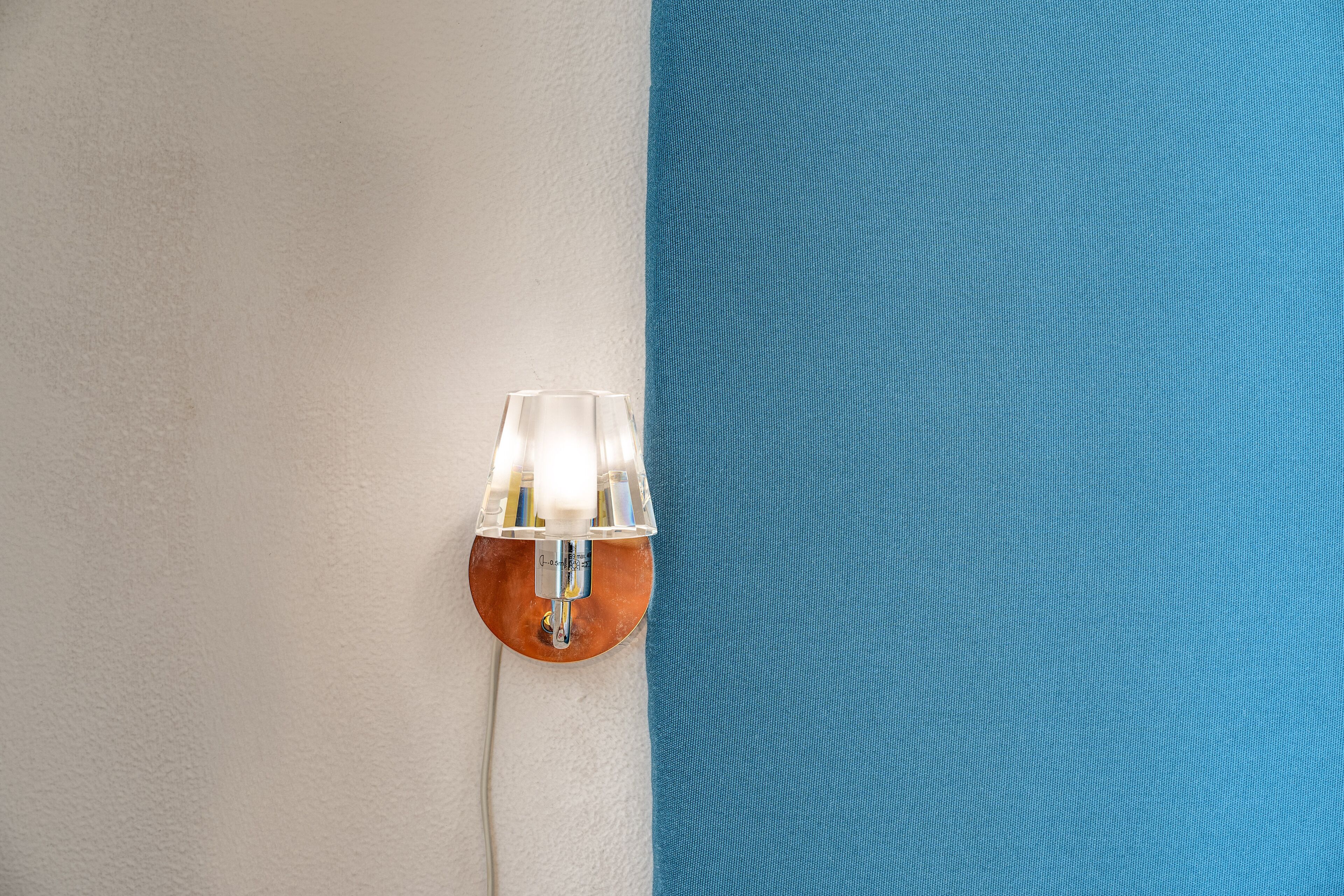 A wall with a light fixture and a blue fabric.