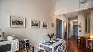 Un comedor con una mesa blanca para cuatro personas, microondas y cafetera sobre una encimera de madera.