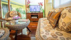 A living room with a sofa, a wicker coffee table, and a television. - TL Residence (Chiang Mai)