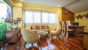 A spacious living area with a sofa set, wicker chairs, a coffee table, and a desk with a computer. - TL Residence (Chiang Mai)