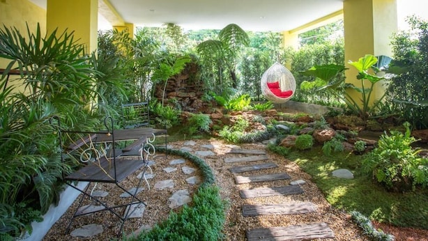 A garden with a stone pathway, hanging chair, and various plants. - TL Residence (Chiang Mai)
