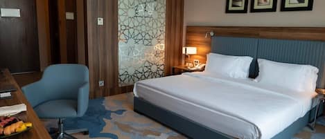 Ein Hotelzimmer mit einem Bett, einem Schreibtisch, einem Stuhl und einem Nachttisch mit Lampe.