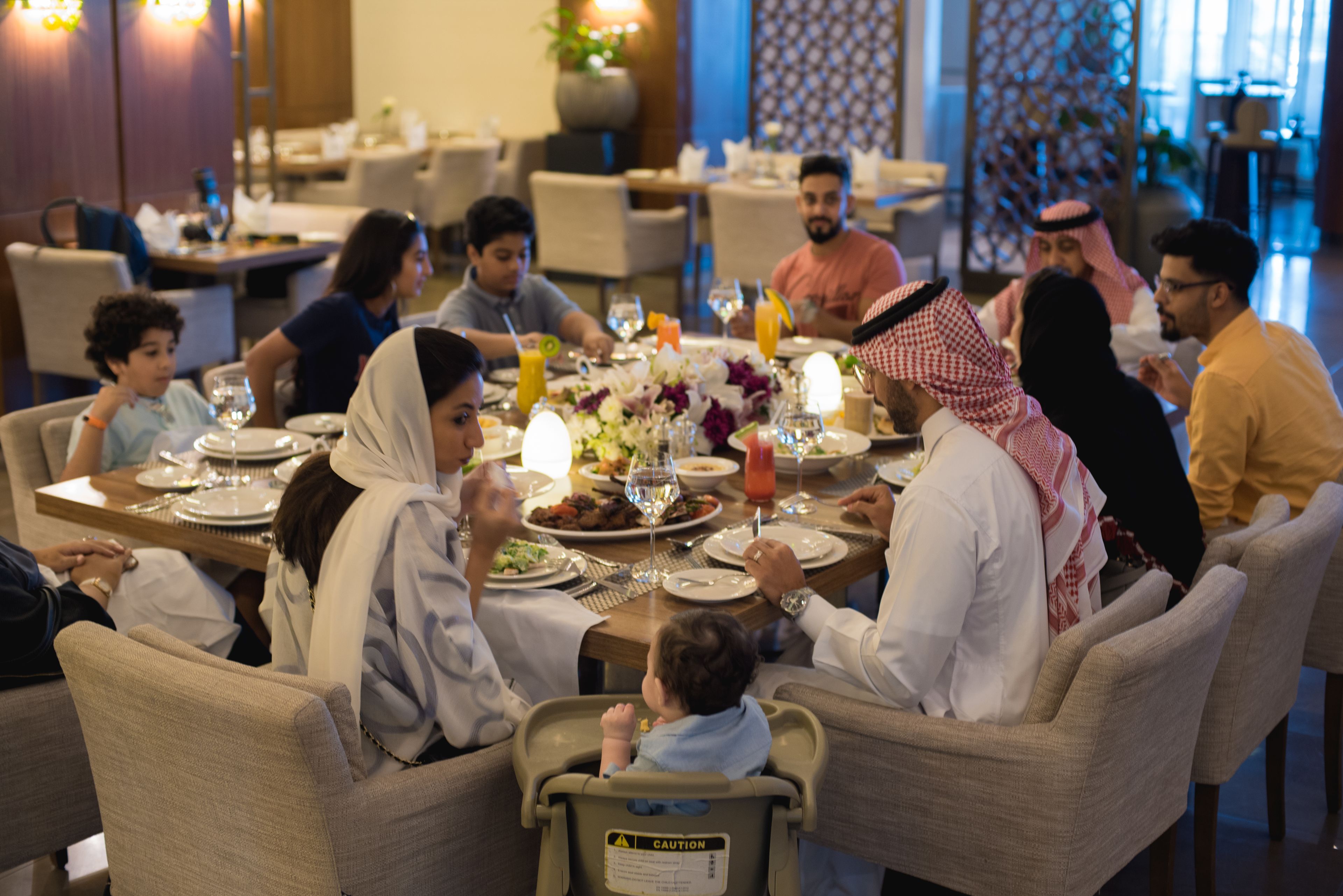 Eine Gruppe von Personen speist in einem Restaurant, auf dem Tisch befinden sich verschiedene Gerichte und Getränke.
