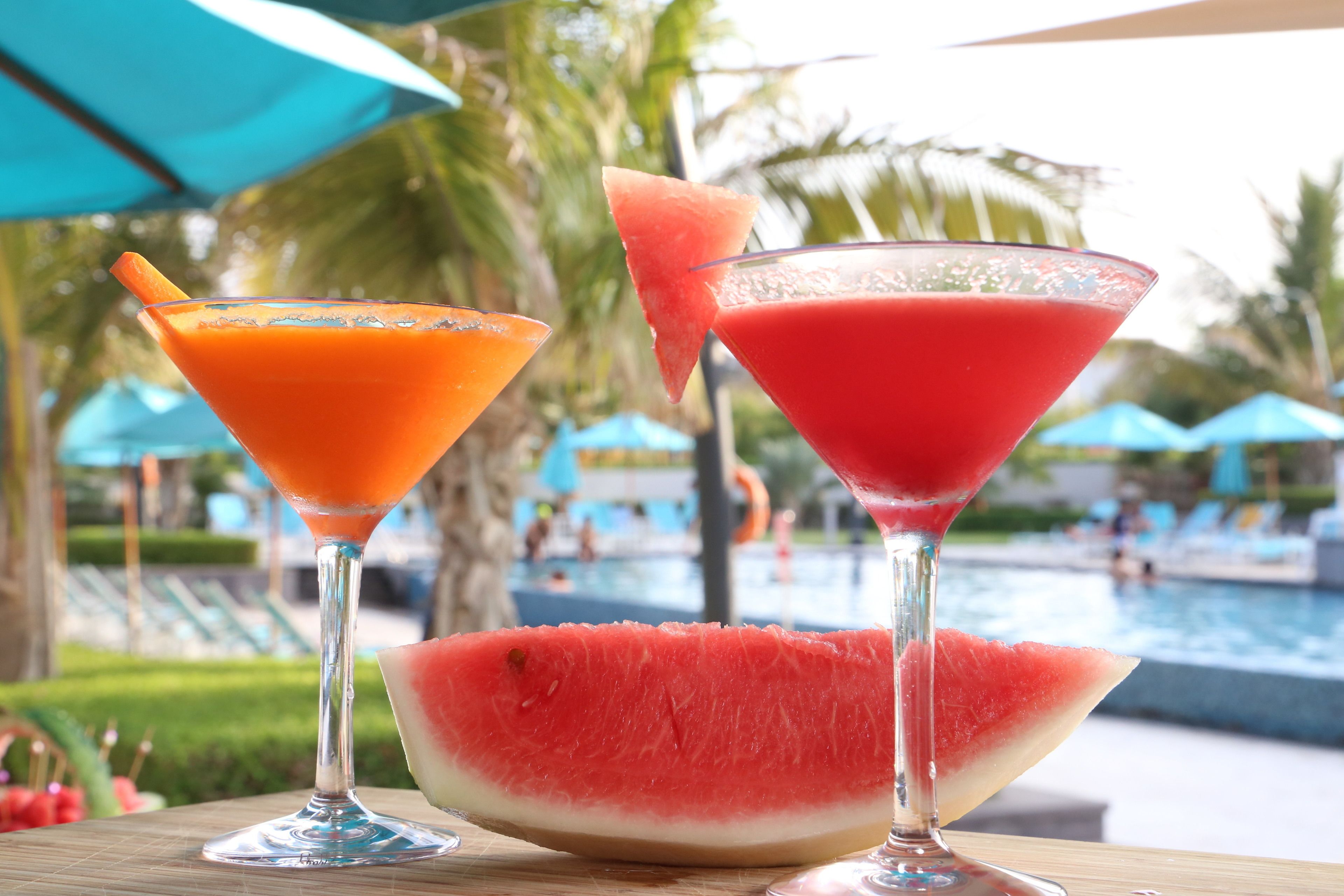 Two cocktails in martini glasses with a slice of watermelon on the table.
