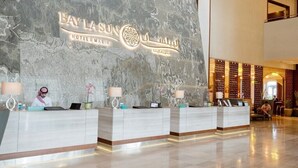 A hotel reception area with a marble wall and a reception desk. - Bay La Sun Hotel & Marina (Rabigh)