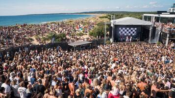 Un evento concurrido en la playa, con escenario y público.