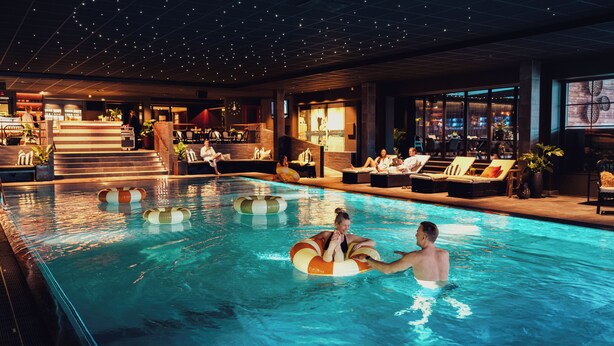 An indoor swimming pool with lounge chairs and a bar area. - Hotel Tylösand (Halmstad)