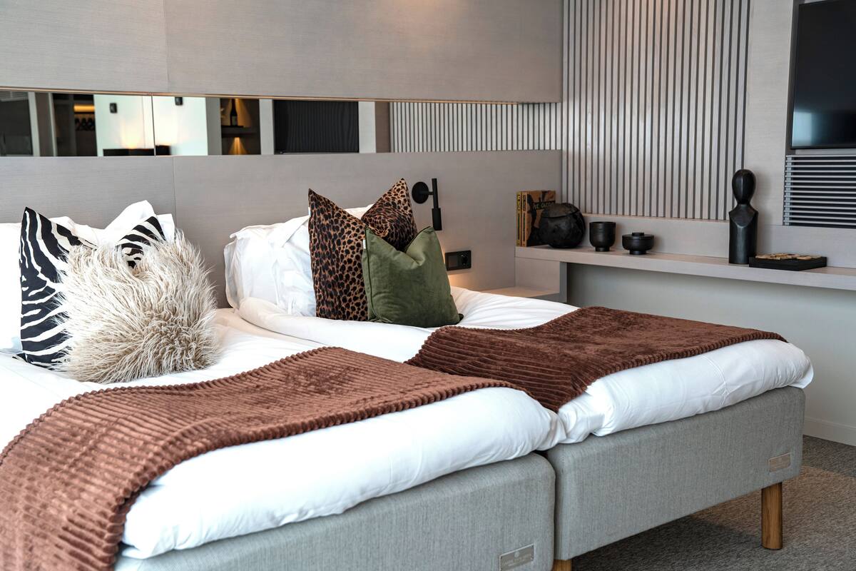 A modern bedroom with a bed, pillows, a bedside table, and a wall-mounted TV.