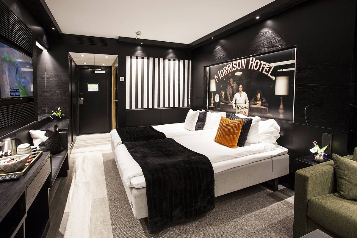 A modern hotel room with a large bed, a desk with a computer, and a television.