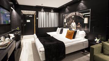 Quarto de hotel moderno com uma cama grande, uma escrivaninha com computador e televisão.