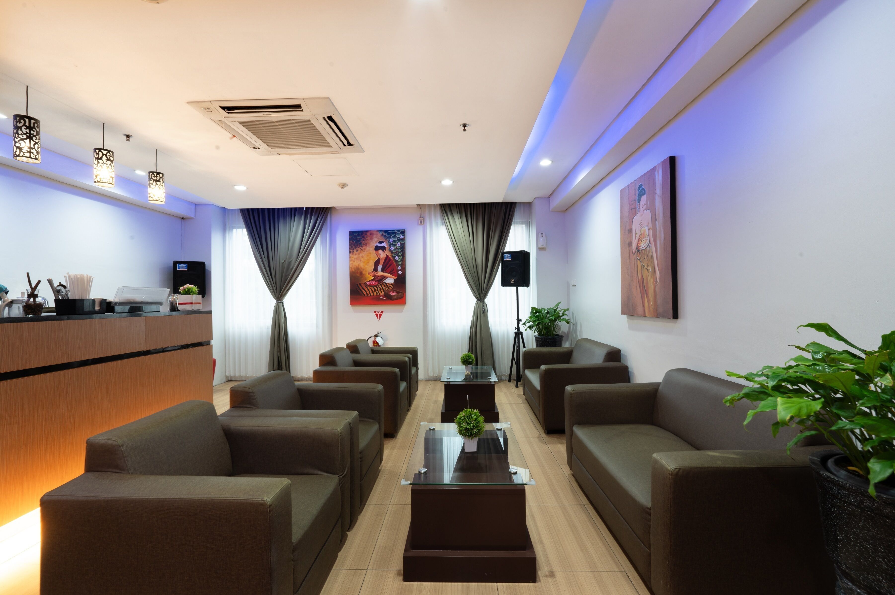 Un moderno hall de hotel con sofás, una recepción y un cuadro grande en la pared.
