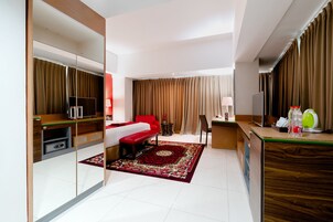 A hotel room with a bed, a desk, a mirror, a TV, and a bathroom.