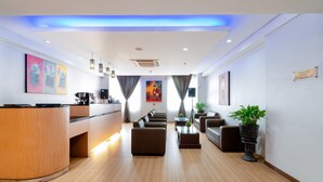 A modern hotel lobby with a reception desk, seating area, and artwork on the walls. - Atrium Premiere Hotel (Yogyakarta)