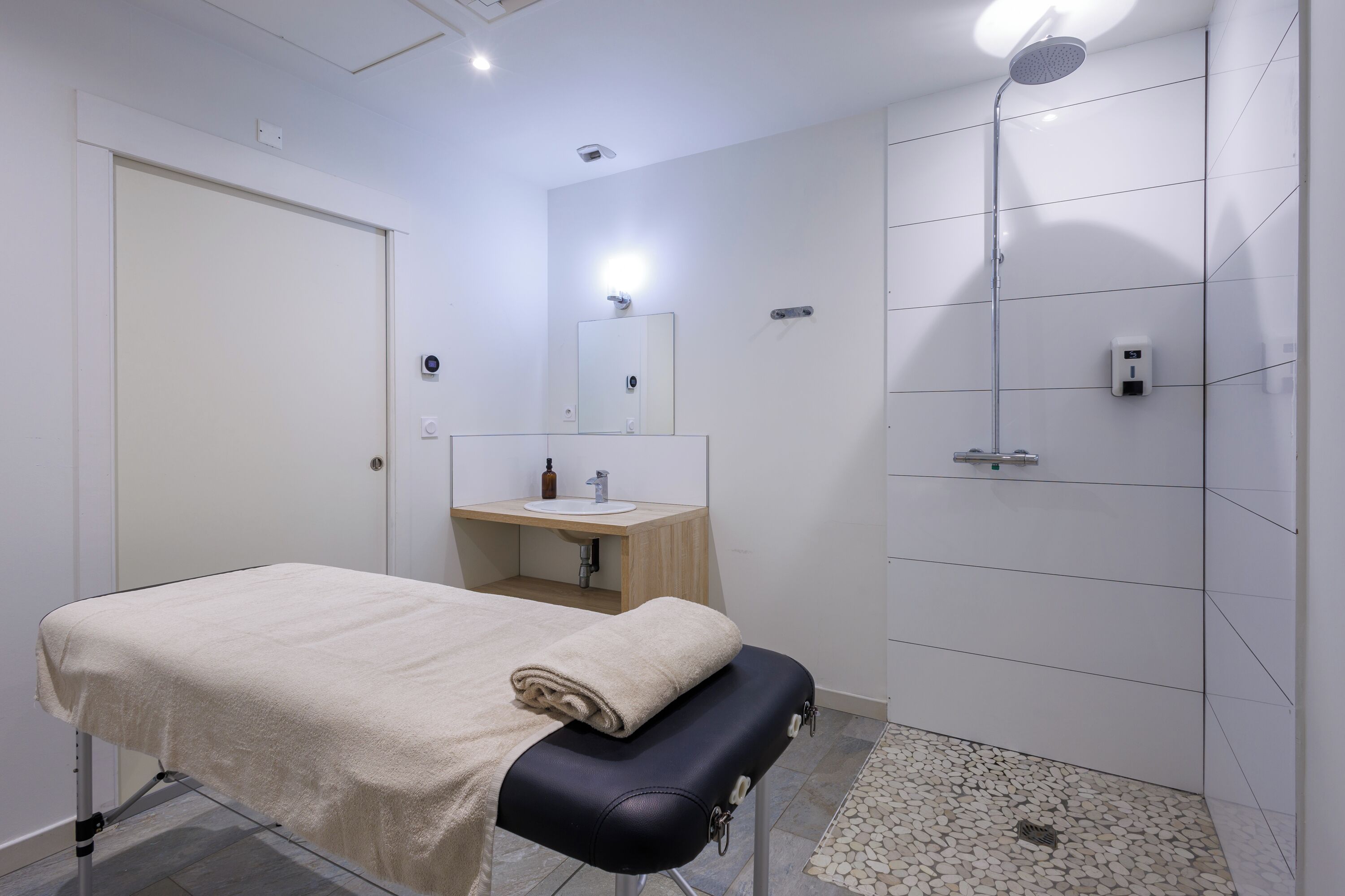 Een moderne badkamer met een bed, wastafel, spiegel en douche.