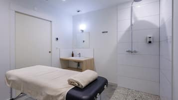 A modern bathroom with a bed, a sink, a mirror, and a shower.