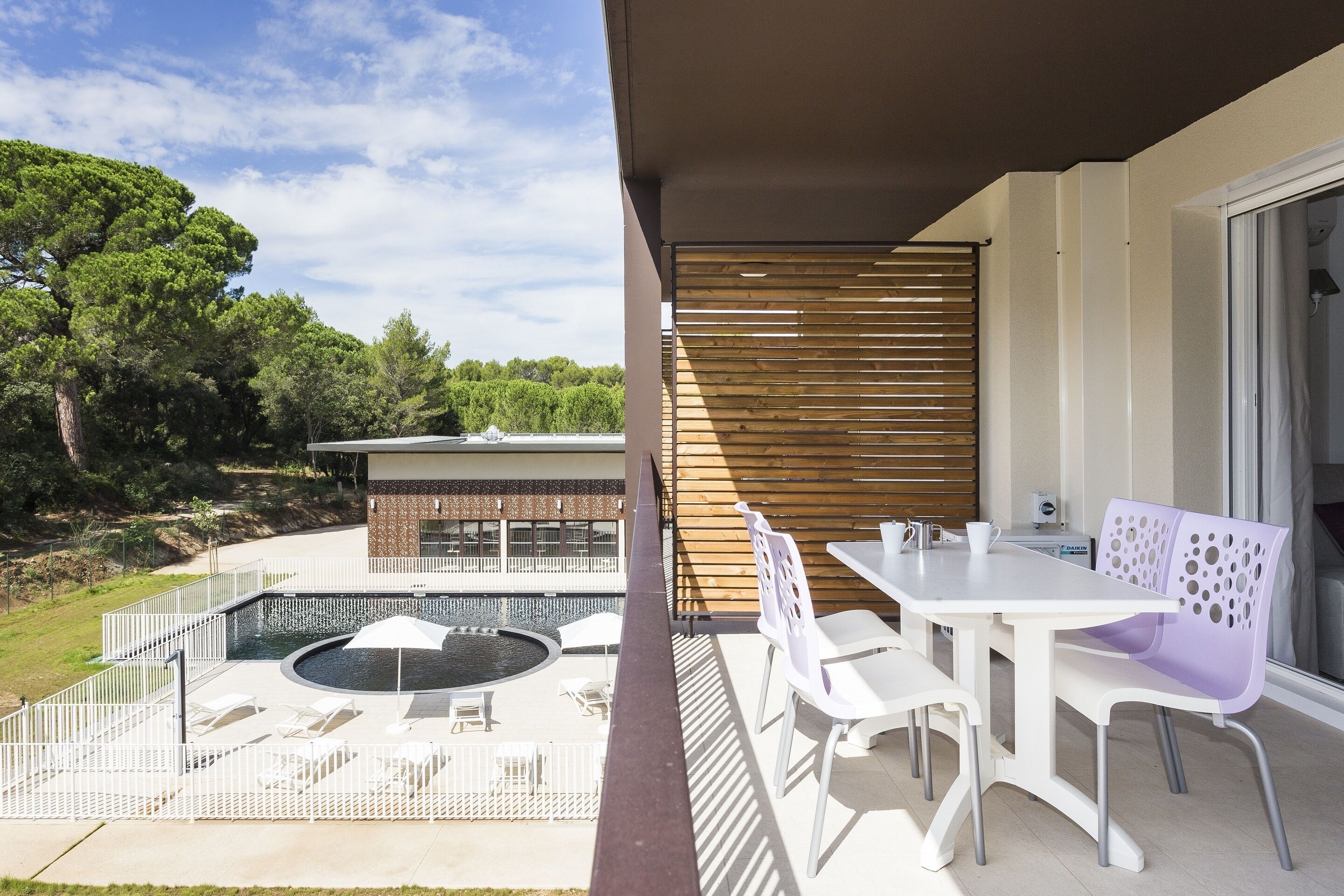 An outdoor patio with a pool, white furniture, and a wooden fence.