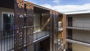 Um edifício com vários andares, varandas, grades de metal e um céu claro.