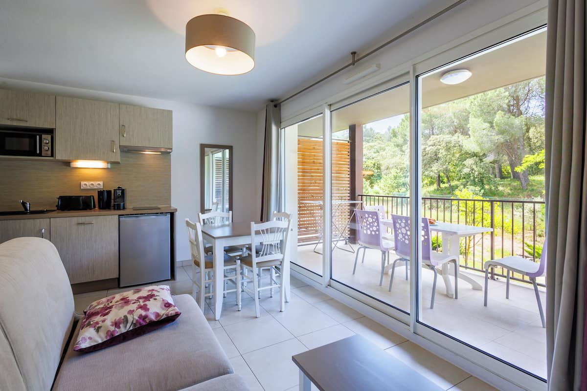 A modern kitchen with a dining area and a balcony with outdoor furniture.