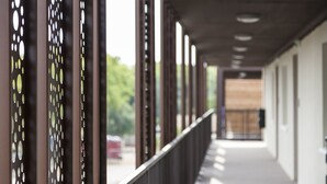 Um corredor com corrimão de metal e painéis decorados, que leva a uma porta com painel de madeira.