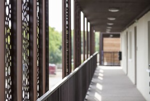 Um corredor com corrimão de metal e painéis decorados, que leva a uma porta com painel de madeira.