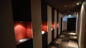 A hotel corridor with checkered flooring, red illuminated niches, and a dark door at the end. - Hotel Fosse Himeji (Himeji)