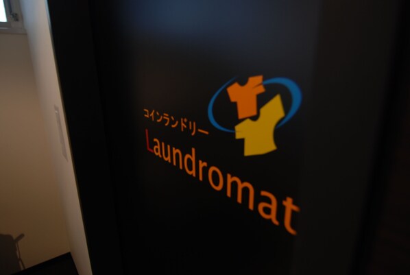Una pared con el logotipo y el nombre 'Laundromat' en inglés y japonés.