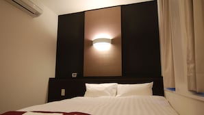 A hotel room with a bed, a wall-mounted light, and a window with curtains. - Hotel Fosse Himeji (Himeji)