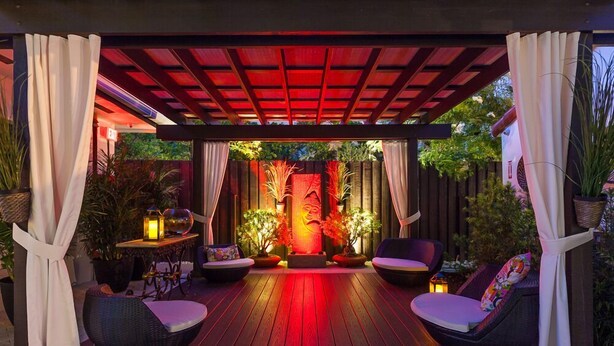 A covered patio area with wooden flooring, two cushioned seating areas, and a central decorative light fixture. - Bars B&B South Beach Miami Boutique Hotel (Miami Beach)