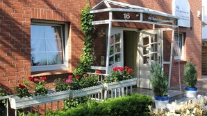 A hotel entrance with a number 16 sign, a covered waiting area, and a brick facade. - Hotel Altenwerder Hof (Hamburg)