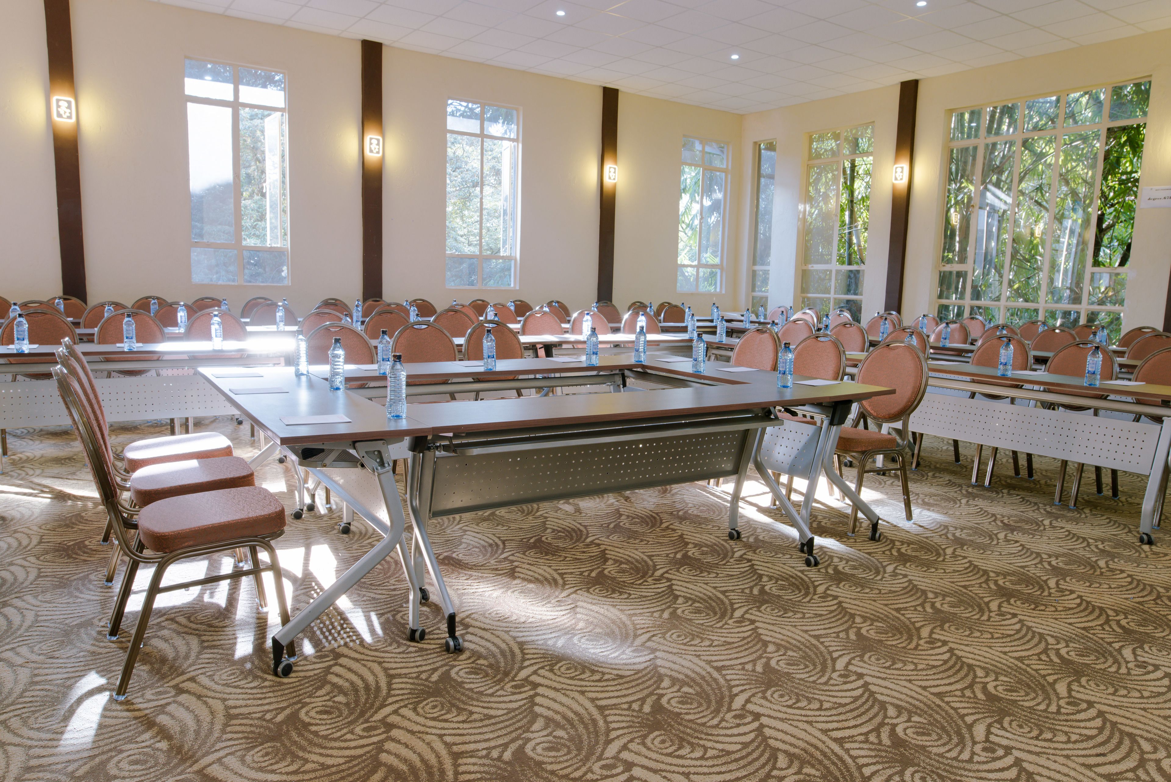 A conference room with multiple tables and chairs, large windows, and a patterned carpet.