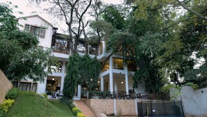 A multi-story building with a covered outdoor area, steps leading up to the entrance, and a trampoline in the garden. - West Wood Hotel (Nairobi)