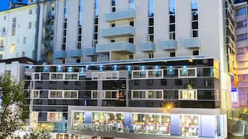Un hôtel à plusieurs étages au design moderne, doté de balcons et d’un restaurant situé au rez-de-chaussée.