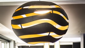 A modern interior with a spherical hanging light fixture, vibrant seating, and a reception area. - Hôtel Astrid (Lourdes)