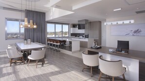 Une cuisine moderne dotée d’un grand îlot central, de tabourets de bar et d’un coin repas avec une longue table et des chaises.