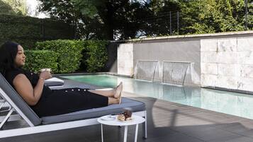 Una piscina al aire libre, sombrillas, sillones reclinables de piscina
