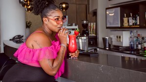 Une personne assise au bar, avec un verre, un téléphone et un appareil à café en arrière-plan.