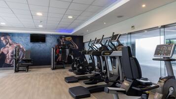 Un gimnasio con cintas de correr, elípticas y máquinas de pesas.