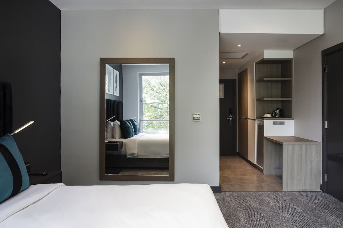 Een moderne hotelkamer met een bed, een bureau en uitzicht op de omgeving.