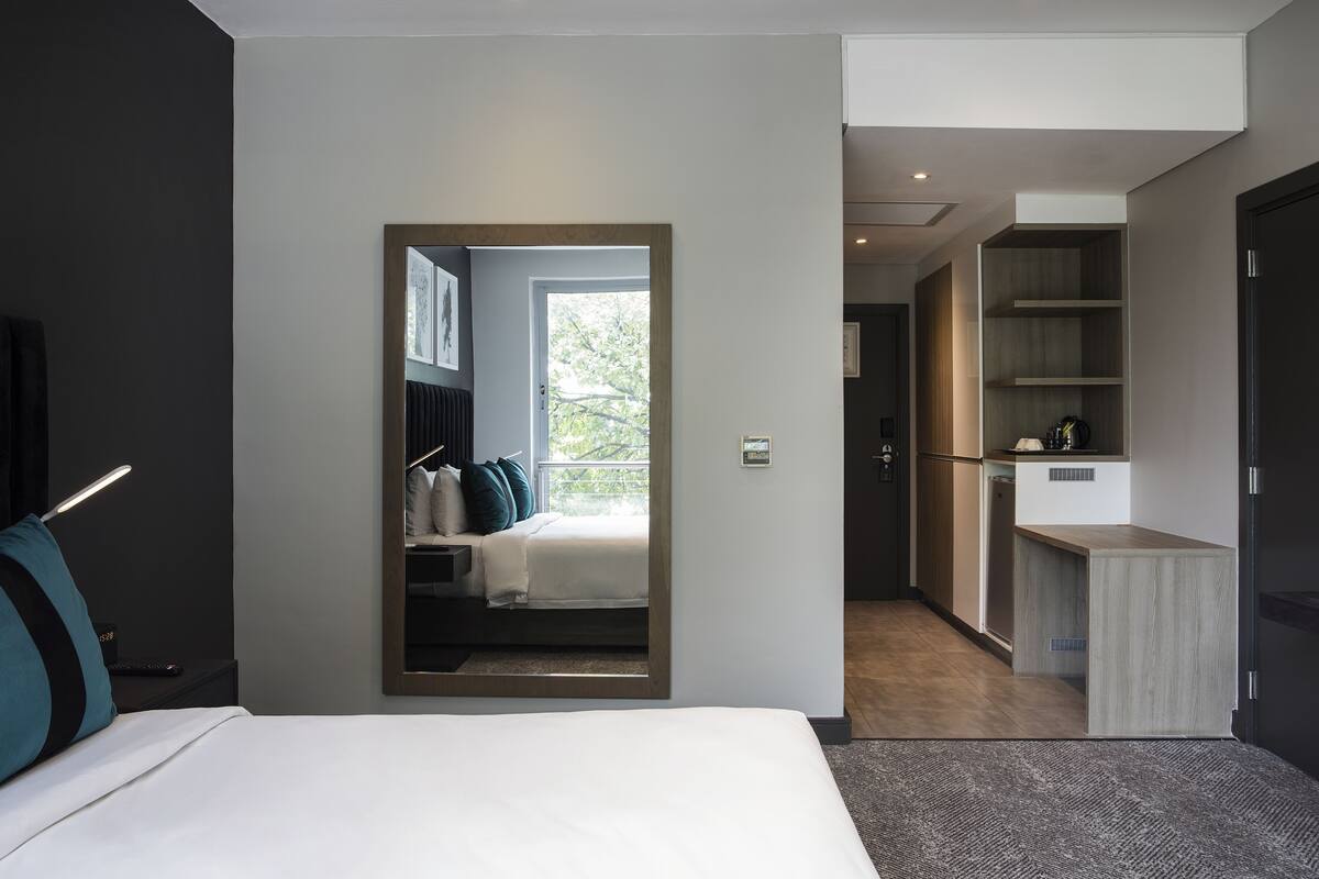 Een moderne hotelkamer met een bed, een bureau en uitzicht op de omgeving.