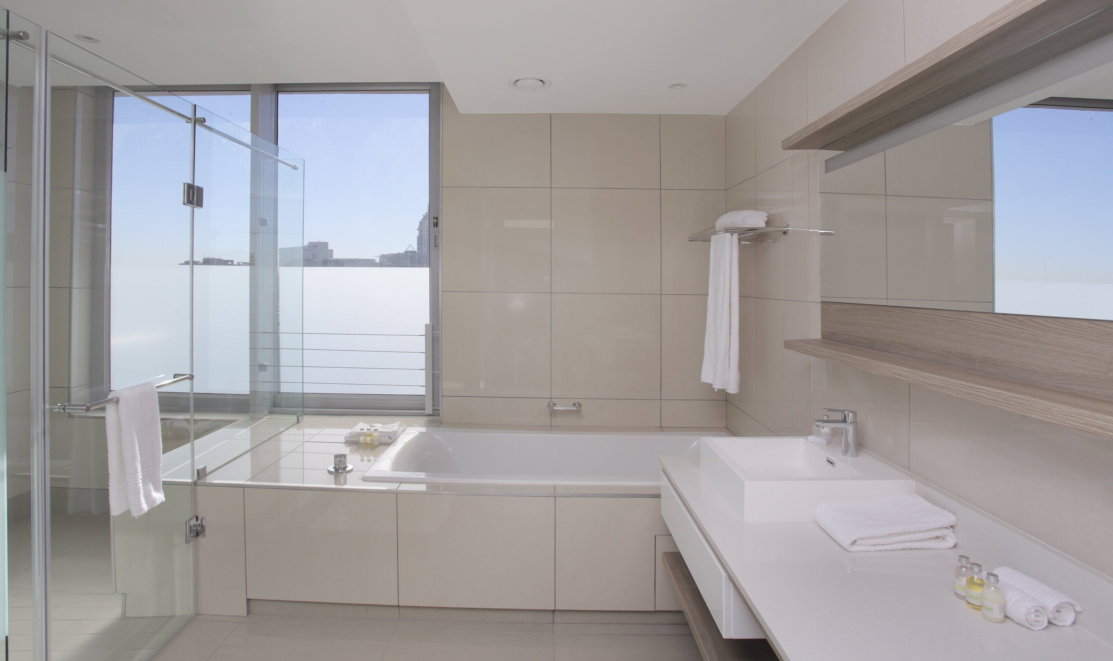 Un baño moderno con ducha de vidrio, una bañera grande y un tocador con espejo.