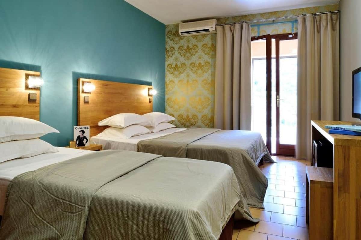 Une chambre d’hôtel avec deux lits, un bureau et une télévision.