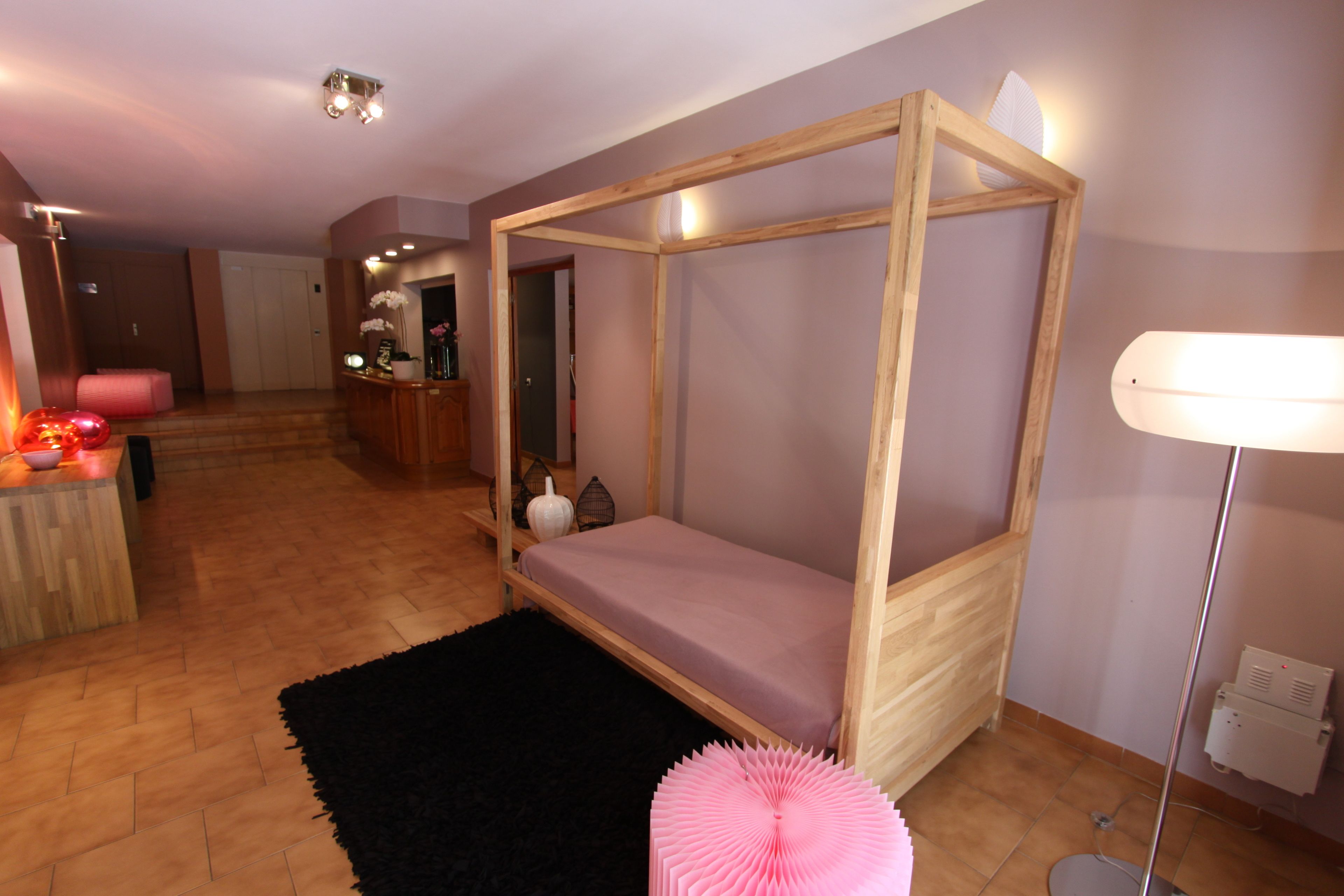Un dormitorio con una cama con dosel de madera, una alfombra negra y una lámpara de noche.