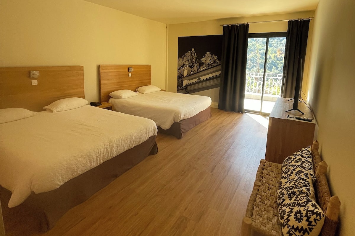 Une chambre d’hôtel avec deux lits, un canapé, une petite table et une vue sur un balcon.