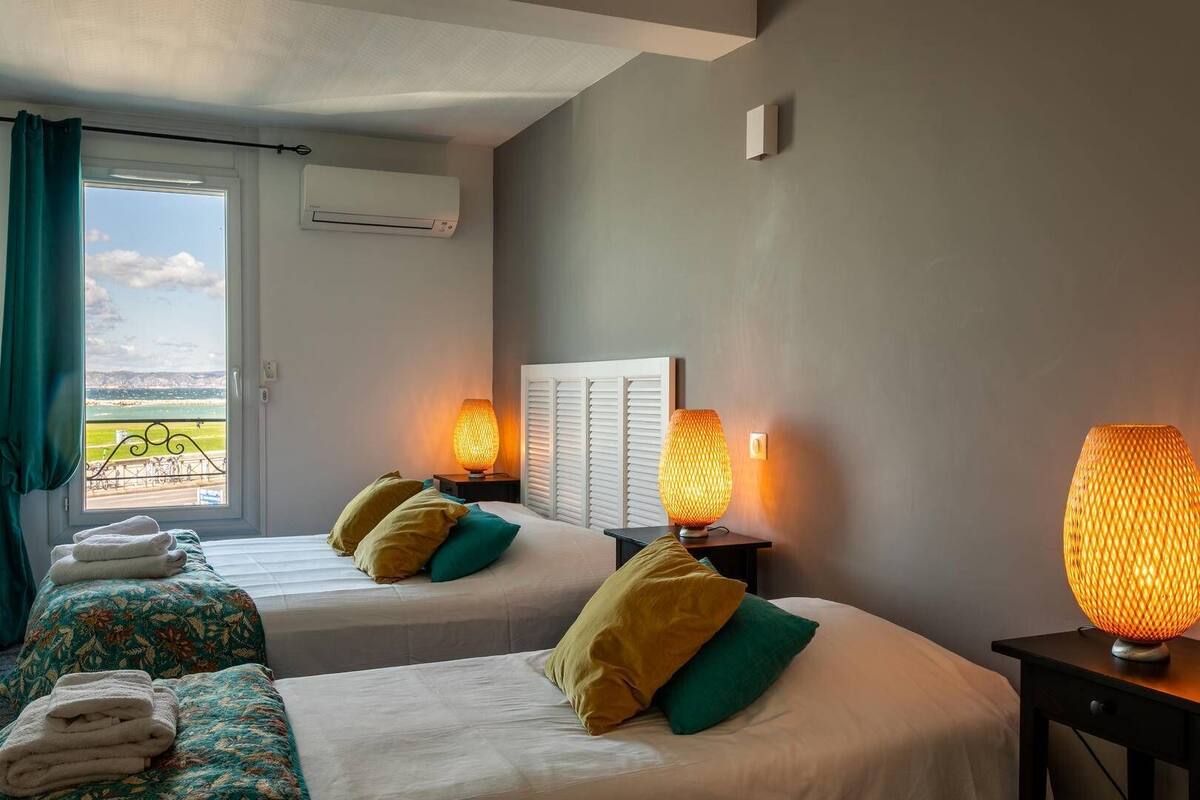 A hotel room with two beds, a window with a view, and two table lamps.