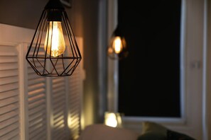Une pièce avec un luminaire suspendu et une fenêtre équipée de stores.