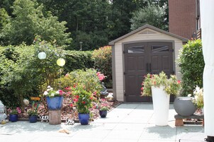 Un jardín con plantas en macetas y un cobertizo.