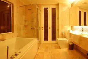 Een aparte badkuip en douche, een bubbelbad, een regendouche