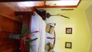 Una habitació amb un llit, un ram de flors en un vas, i dos quadres penjats a la paret.