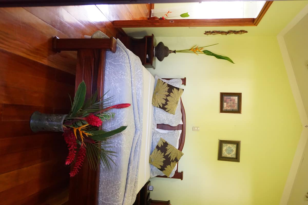 A room with a bed, a vase with flowers, and two wall-mounted picture frames.